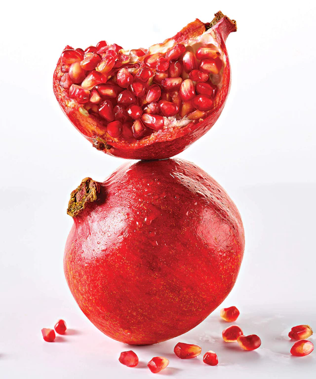 A whole pomegranate and a broken open pomegranate