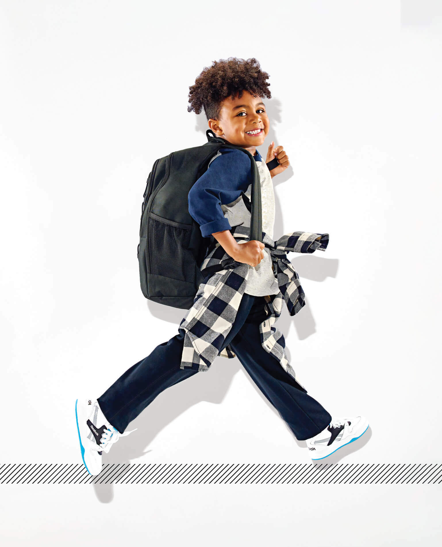 A young boy striking a pose in a backpack headed back to school.