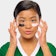 A woman applying a beauty face mask under her eyes like a football player.