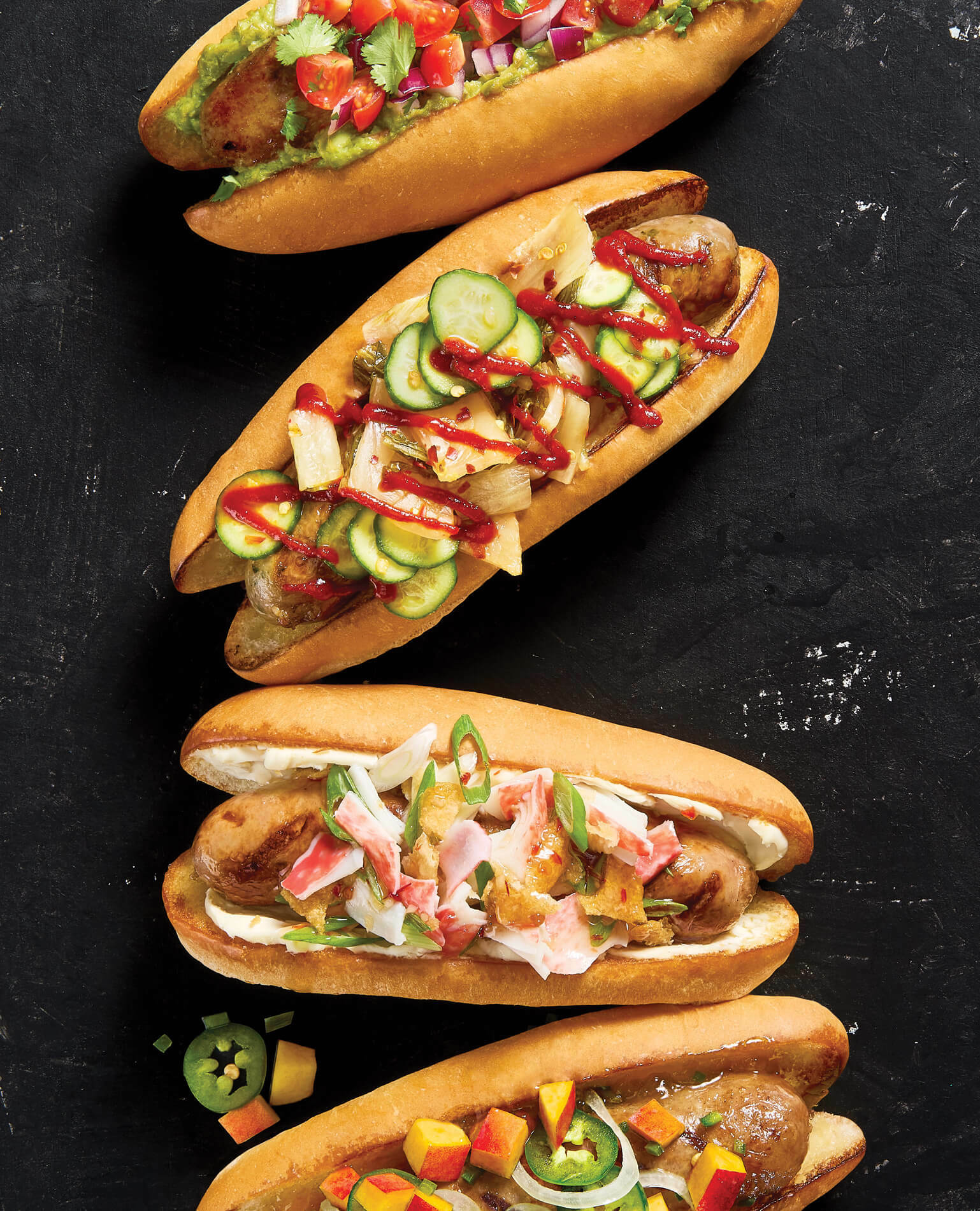 Four bratwursts on buns with various unique toppings.