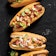 Four bratwursts on buns with various unique toppings.