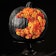 A crescent moon made from orange flowers adorns a pumpkin painted all black.