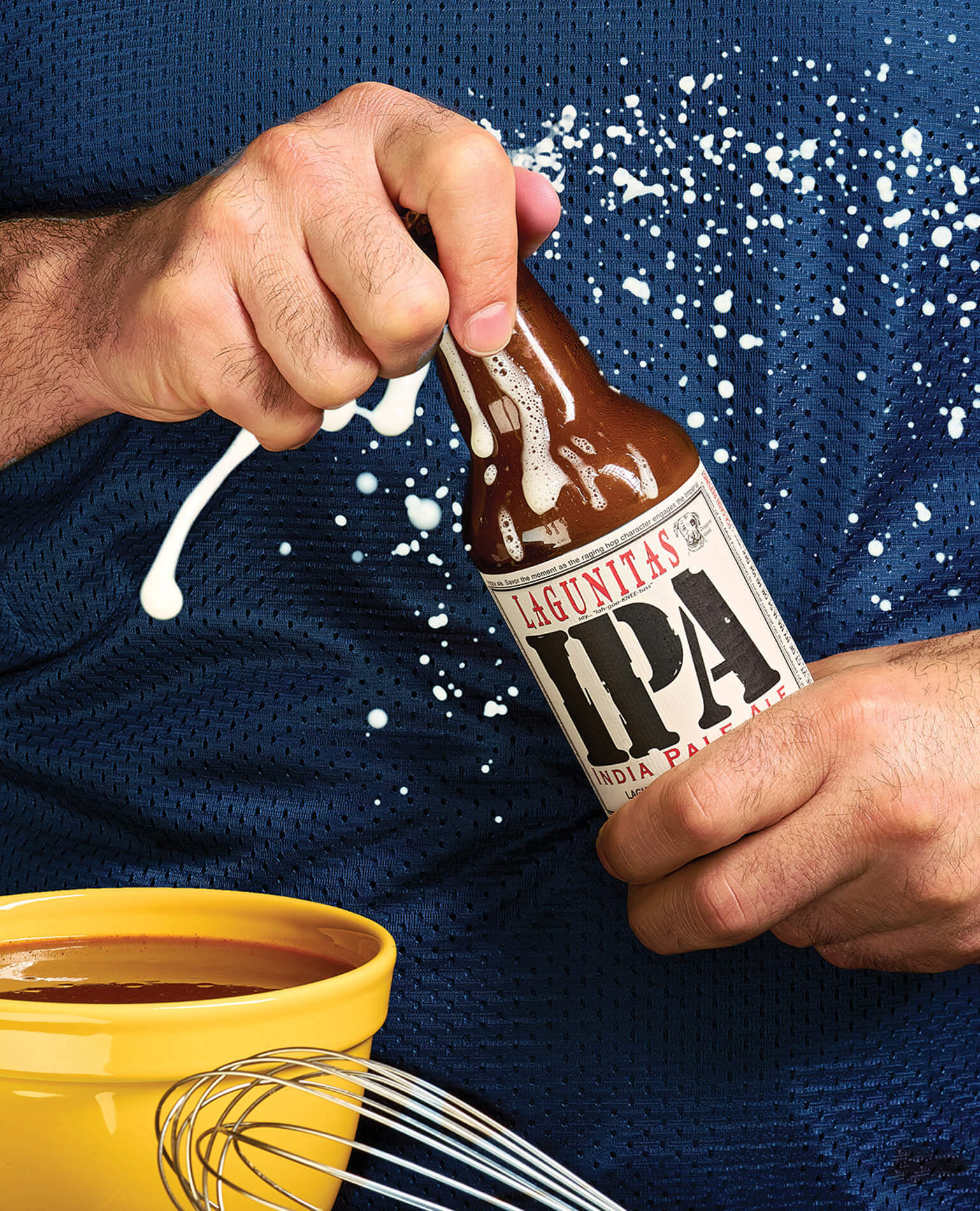 A man's hands opening a bottle of beer as it sprays suds all over.
