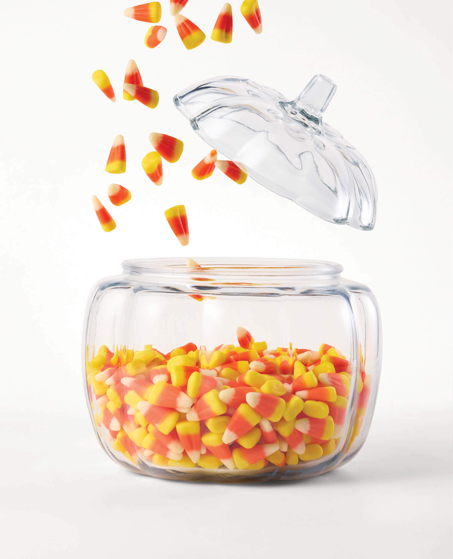 Candy corn pouring into a glass candy dish.