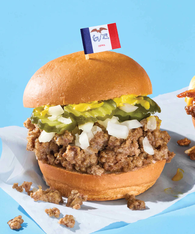 A loose meat sandwich with a small flag of Iowa stuck into the top of the bun.