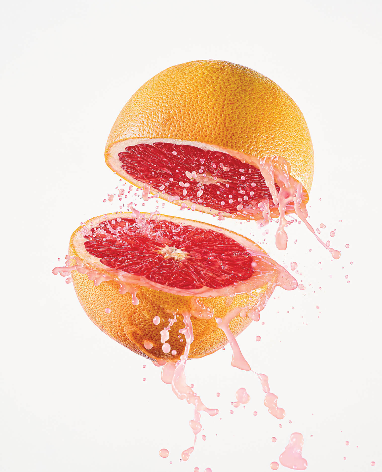 A fresh grapefruit splitting in half to reveal its juicy center.