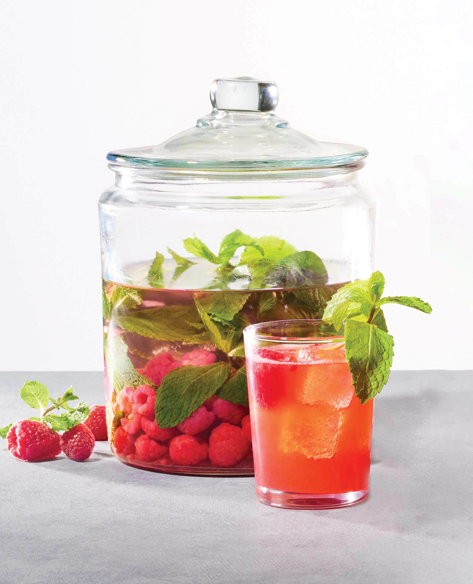 A jar of raspberry infused vodka behind a cocktail using the infused vodka.