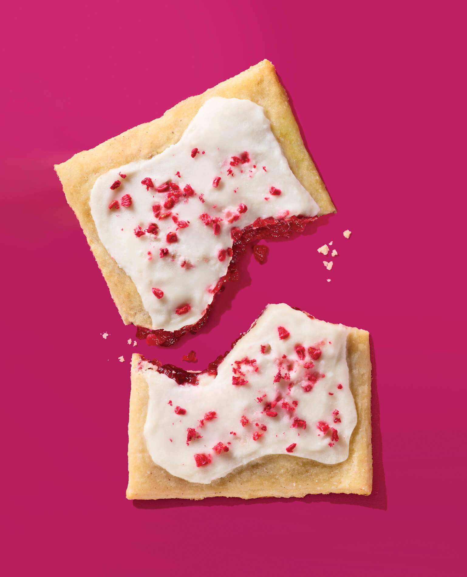 A broken up breakfast pastry on a pink background.