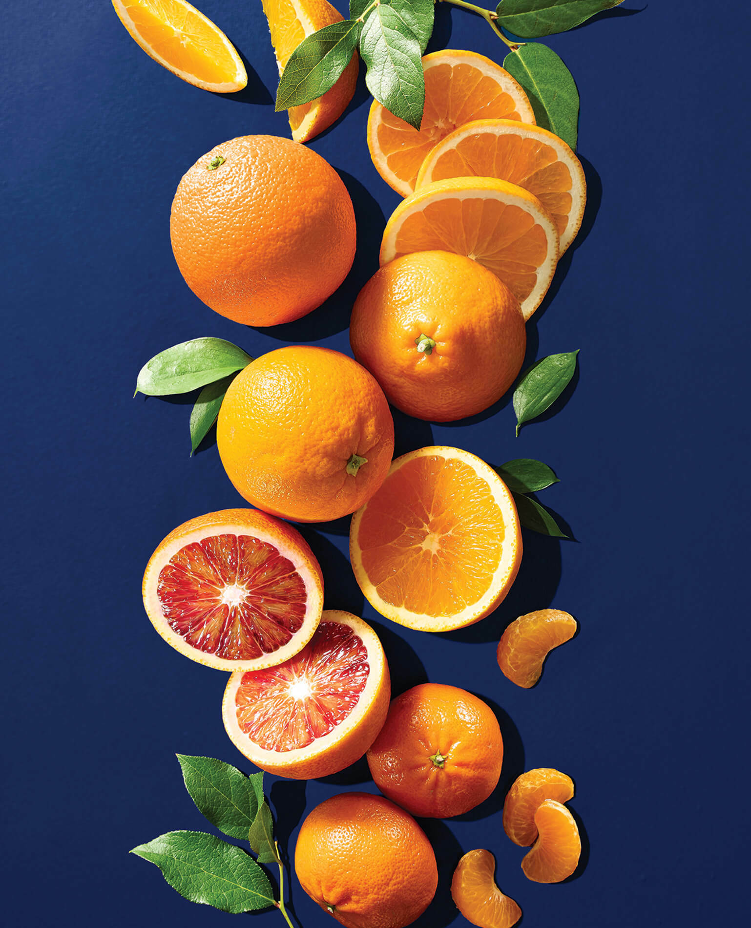 Slices of various types of oranges on a blue background.