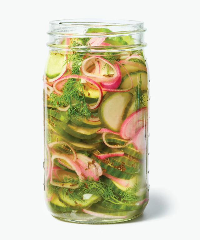 Glass jar filled with pickles, onions and spices