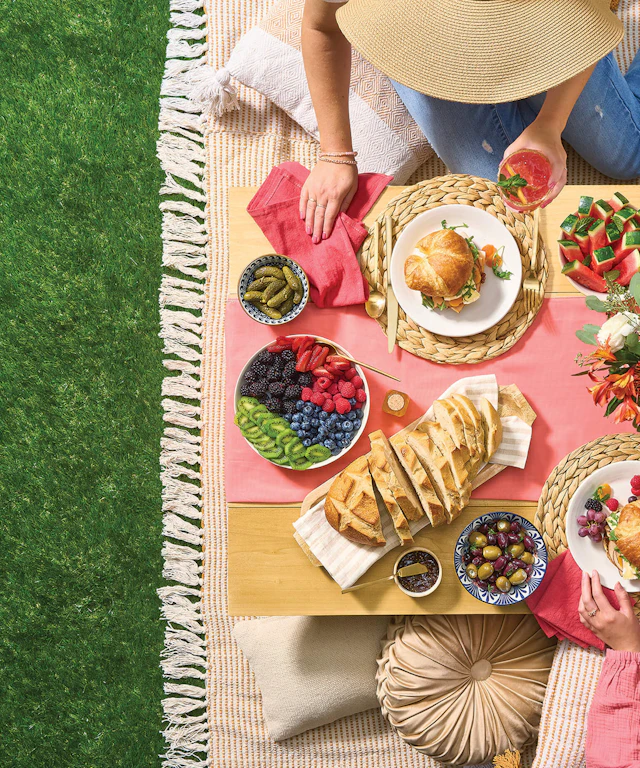 A woman sitting at a posh picnic spread on the grass from overhead.