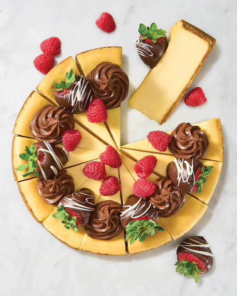 A Chocolate Covered Strawberry Cheesecake sliced, with a piece missing