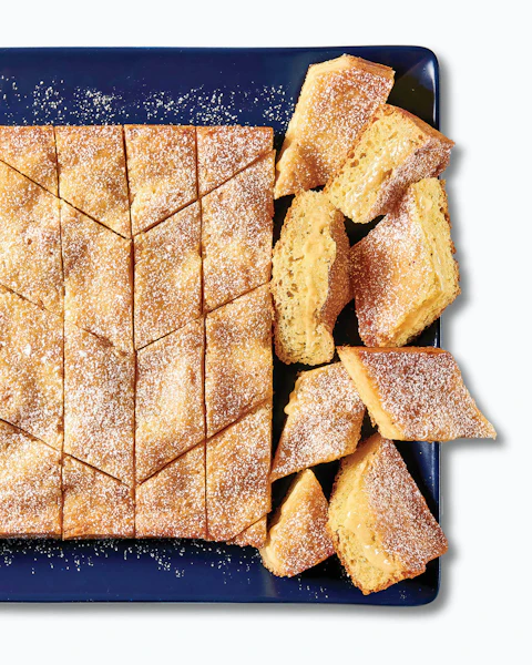 A sliced Gooey Buttery Cake on a blue platter