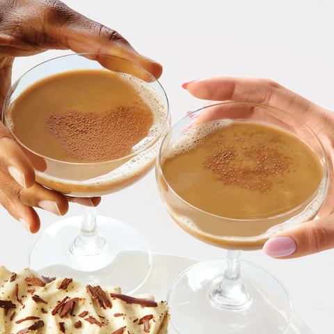 A man's and woman's hands clinking their Millionaire Coffee Cocktails together