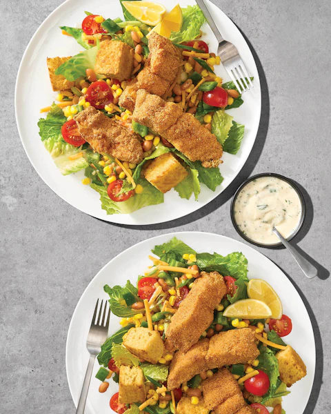 Two plates of Corn Bread Salad with Fried Catfish Tenders