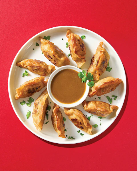 A plate of New Years Dumplings with a dipping sauce