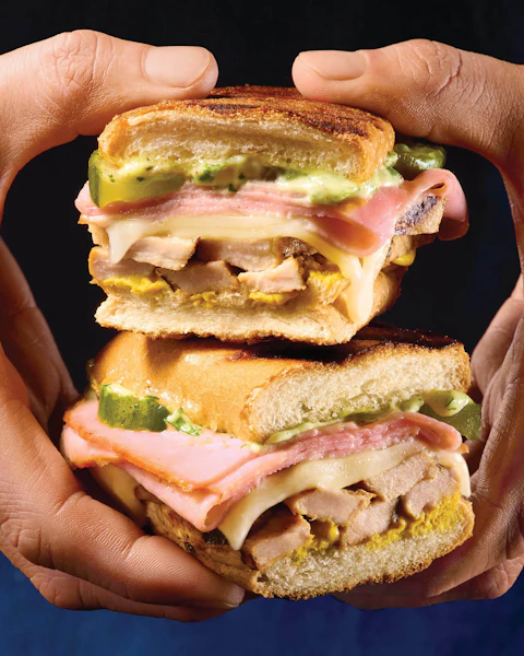 A man's hands holding a Grilled Mojo Cuban Sandwich