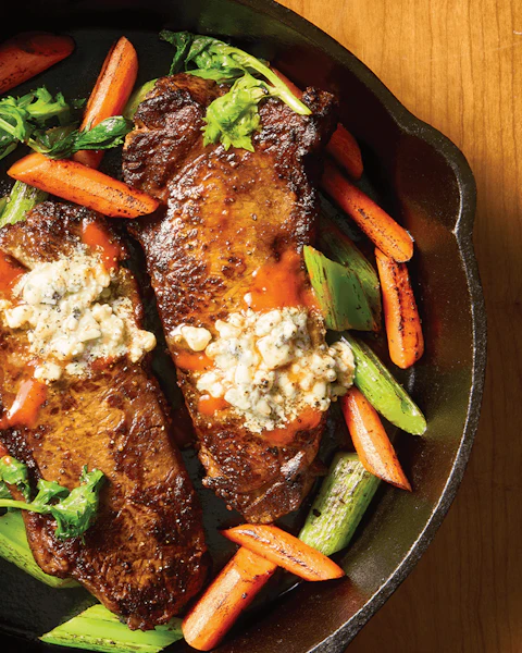 Cast iron skillet of Grilled Buffalo Steaks with Blue Cheese Butter