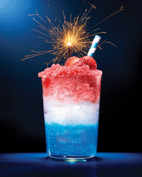 Glass of Red White Blue Frozen Sangria with sparkler on top