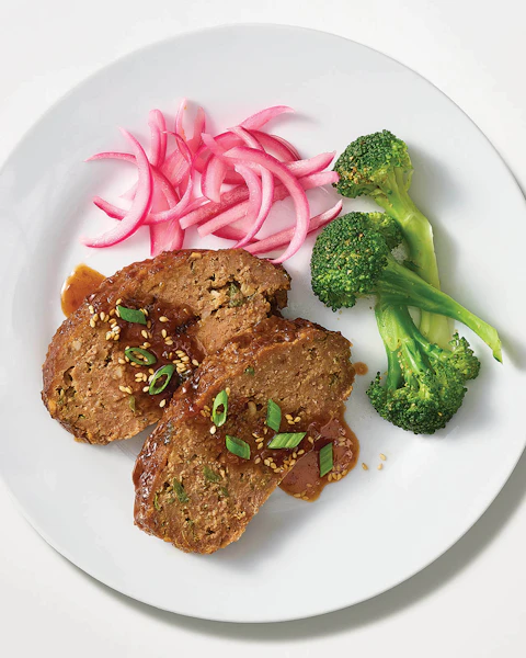 A plate of Korean BBQ Microwave Meatloaf with sides of pickled onions and brocolli.