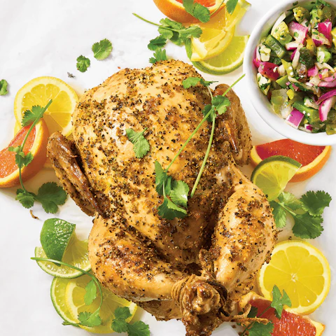A whole Grilled Rose Can Chicken with a cup of Spicy Tomatillo Salsa