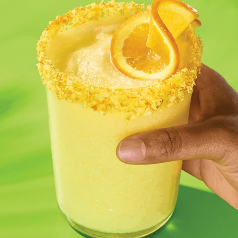 Hand holding a glass of Creamy Coconut Orange Margarita