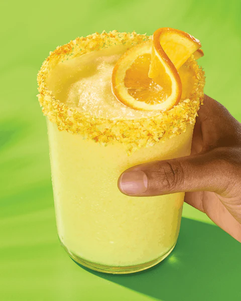 Hand holding a glass of Creamy Coconut Orange Margarita