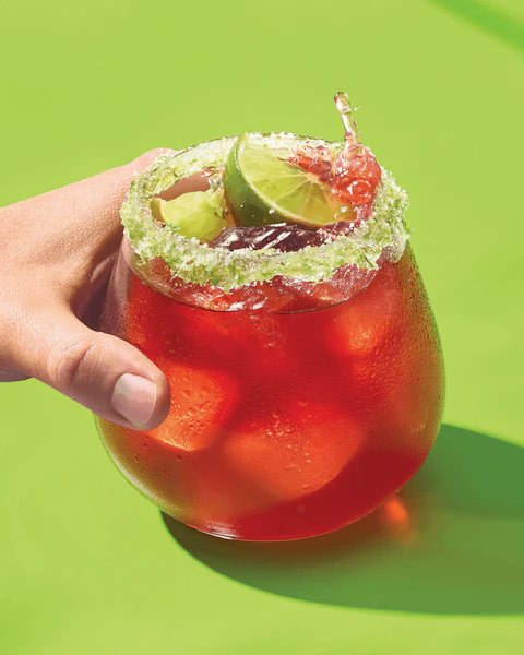 Hand holding a glass of Sparkling Cherry Hibiscus Margarita