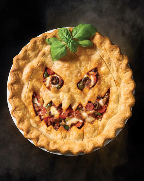 A pizza pot pie cut and decorated to look like a jack-o-lantern for Halloween.