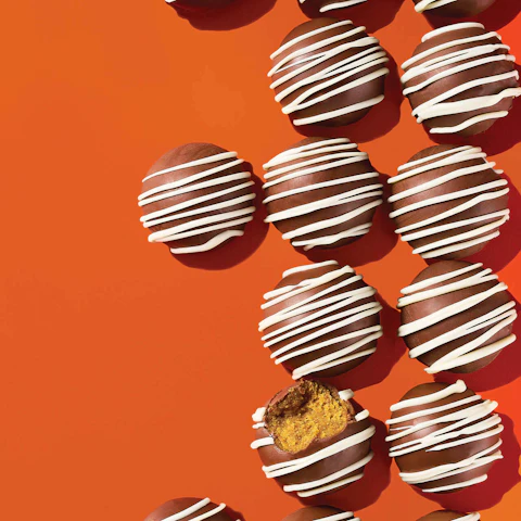 Rows of Salted Caramel Pumpkin Cake Balls on an orange background.