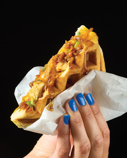 A woman's hand holding a Chicken Sweet Potato Stuffed Waffle Pocket