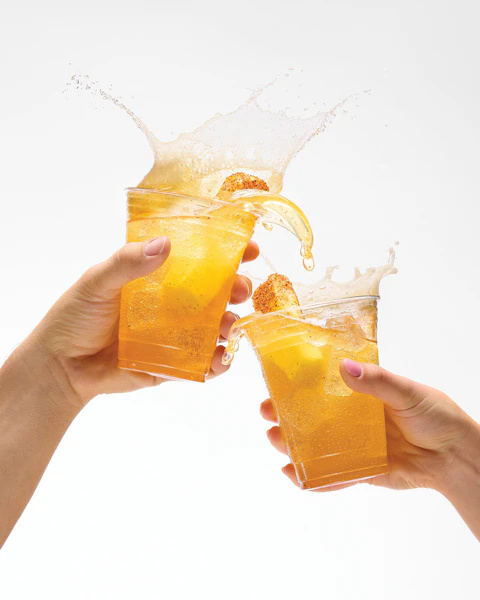 Two glasses of Pineapple and Citrus Chile Chelada being clinked together for a cheers.