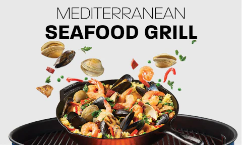Spanish paella in a cast iron skillet on top of a charcoal grill.