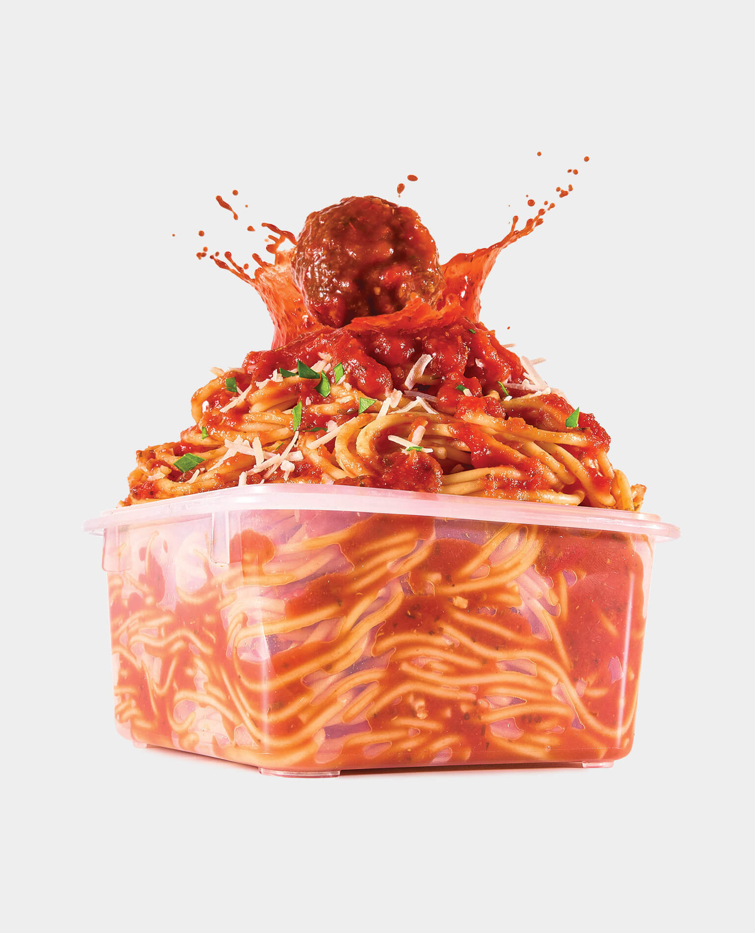 A plastic container filled with pasta being splattered by a meatball.