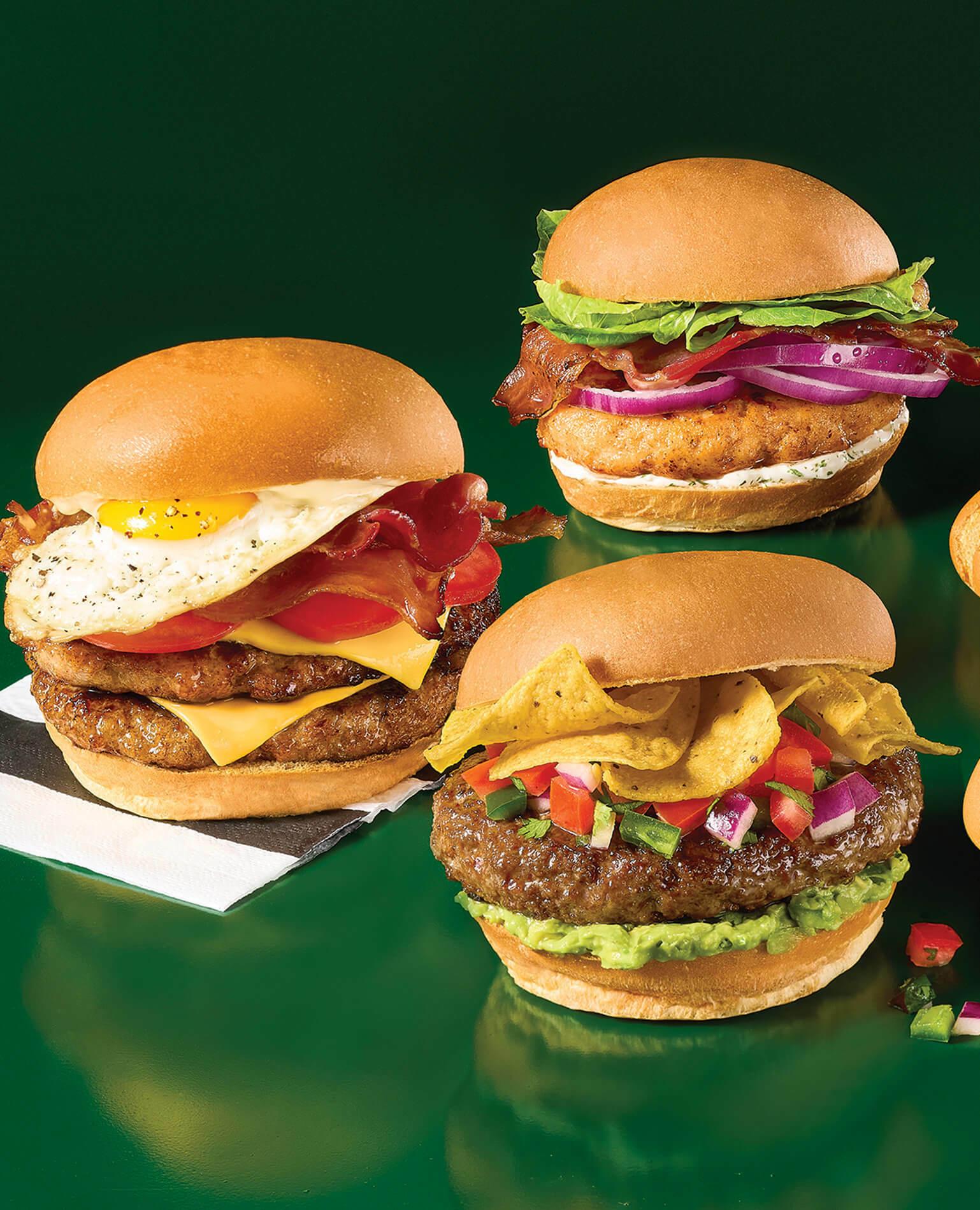Three burger varieties on a green background.