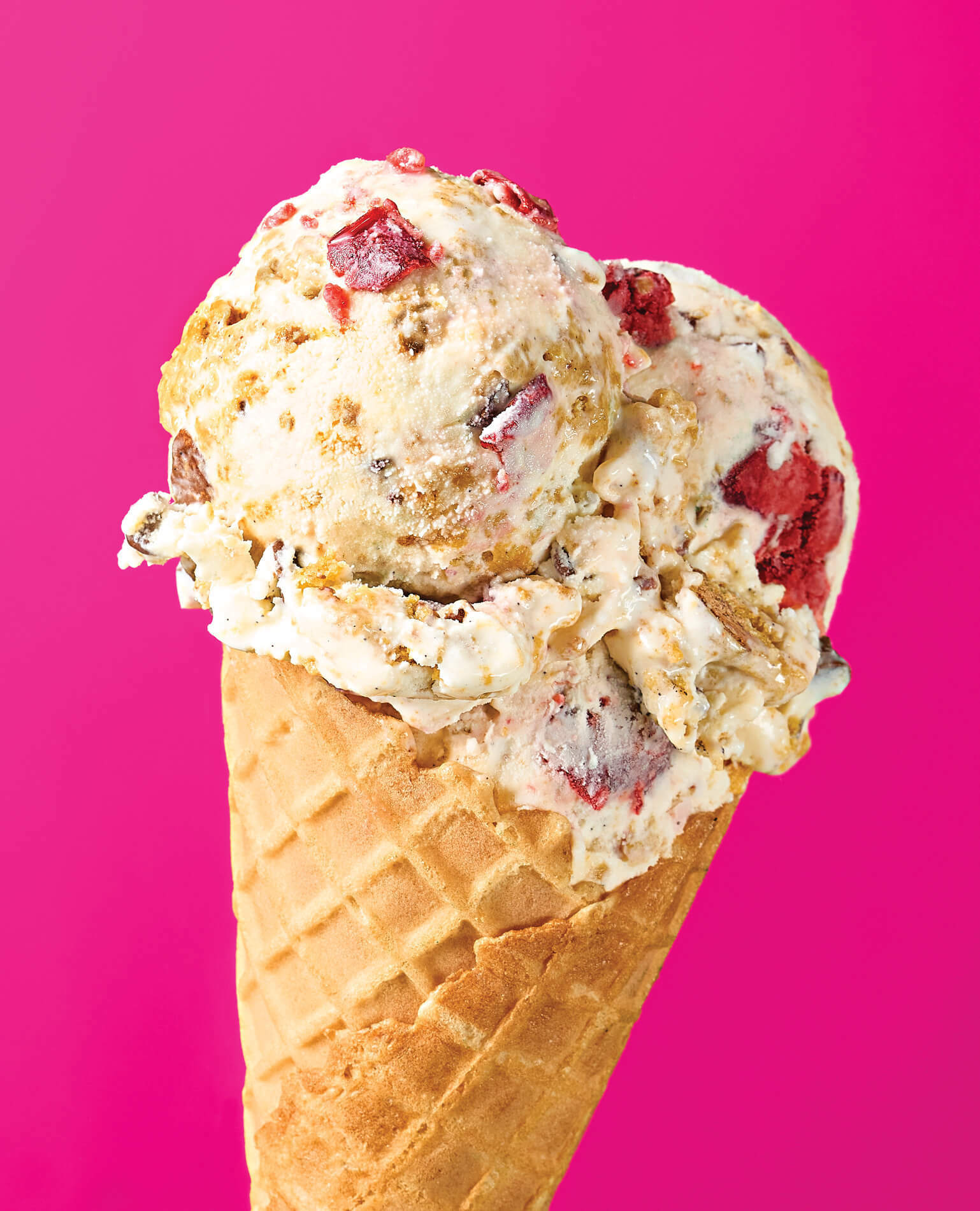 A chunky, fruity ice cream cone on a pink background.